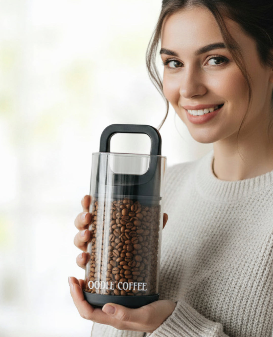 Woman holding aOodle Coffee FreshSeal Bean Vault with coffee beans against a blurred background